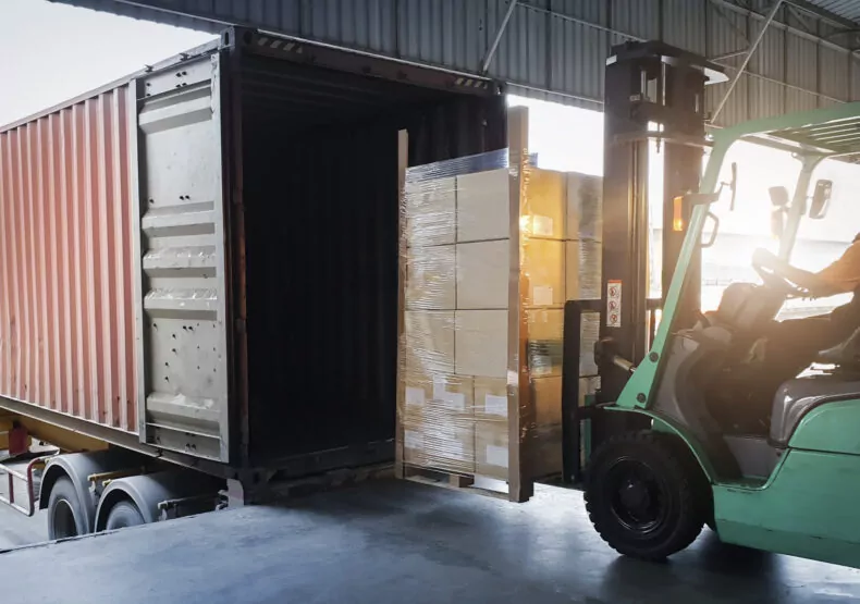 Forklift Tractor Loading Package Boxes into Cargo Container at Dock Warehouse is something a phoenix truck accident attorneys help with in truck accident claims 