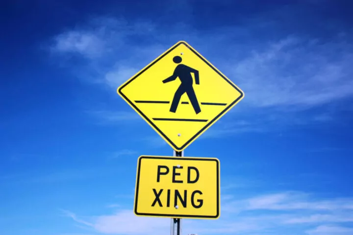 pedestrian crossing sign against blue background sky