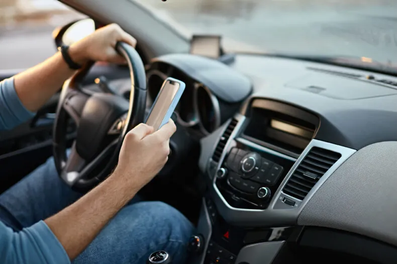 person using cell phone behind the wheel