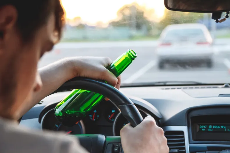 man with a beer bottle behind the wheel
