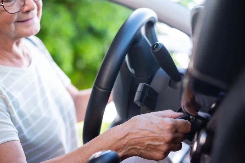 Close-up on senior woman hand in her car holding the key ready for drive and travel