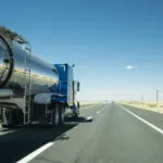 truck with a silver tank trailer passing a passenger car on a highway in Texas