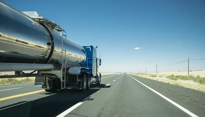 truck with a silver tank trailer passing a passenger car on a highway in Texas